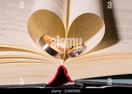 Primo piano di matrimonio anelli tra le pagine di un libro Foto Stock