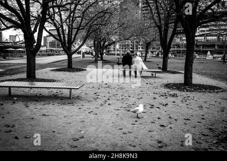 MELBOUR, AUSTRALIA - Nov 16, 2019: Una foto in scala di grigi di una coppia seduta in un parco, Melbourne City LIFE prima della pandemia, Australia Foto Stock