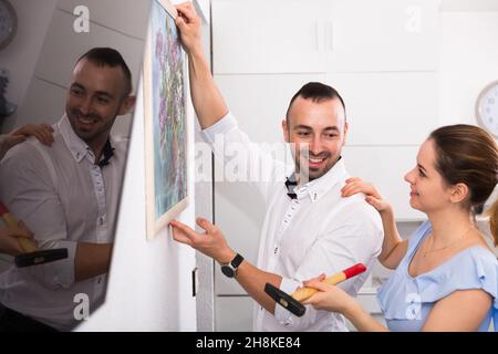 La coppia sta facendo la riparazione e appendere l'immagine sul muro Foto Stock