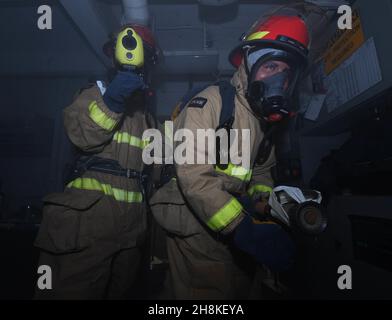 OCEANO PACIFICO (Nov. 24, 2021) Damage Controlman Fireman Tristan Johnson (a sinistra), di Saint Louis, e Aviation Machinist's Mate 3rd Class Isaacs Zero, di Wapato, Washington, simulano la lotta al fuoco durante una perforazione di quartieri generali a bordo di USS Abraham Lincoln (CVN 72). Abraham Lincoln sta conducendo le operazioni di routine nella terza flotta degli Stati Uniti. (STATI UNITI Foto Navy di See Communication Specialist Seaman Sebastian Portieleslopez/Released) Foto Stock