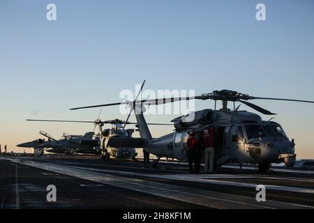 OCEANO PACIFICO (Nov. 13, 2021) i marinai eseguono la manutenzione su un elicottero MH-60 Sea Hawk, assegnato ai "Chargers" di Helicopter Sea Combat Squadron (HSC) 14, sul ponte di volo di USS Abraham Lincoln (CVN 72). Abraham Lincoln sta conducendo le operazioni di routine nella terza flotta degli Stati Uniti. (STATI UNITI Foto Navy di Mass Communication Specialist Seaman Thaddeus Berry/Released) Foto Stock