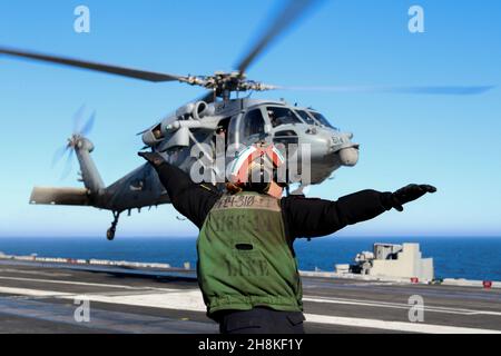 OCEANO PACIFICO (Nov. 11, 2021) Aviation Structural Mechanic Airman Sydney Buckels, di San Diego, assegnato ai “Chargers” di Helicopter Sea Combat Squadron (HSC) 14, fornisce segnali di atterraggio sul ponte di volo a bordo della USS Abraham Lincoln (CVN 72). Abraham Lincoln sta conducendo le operazioni di routine nella terza flotta degli Stati Uniti. (STATI UNITI Foto Navy di Mass Communication Specialist terza classe Louis Lea/Released) Foto Stock