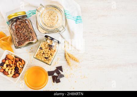Vista dall'alto di vasetti pieni di avena e vari granoli croccanti - frutta secca, noci e cioccolato. Concetto di mangiare sano. Spazio di copia. Foto Stock