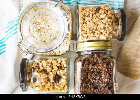 Vista dall'alto di vasetti pieni di avena e vari granoli croccanti - frutta secca, noci e cioccolato. Concetto di mangiare sano. Foto Stock