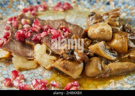 Arrosto di manzo con funghi e semi di melograno. Cucina gourmet francese. Primo piano Foto Stock