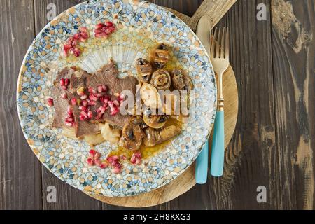 Arrosto di manzo con funghi e semi di melograno. Cucina gourmet francese. Disposizione piatta Foto Stock