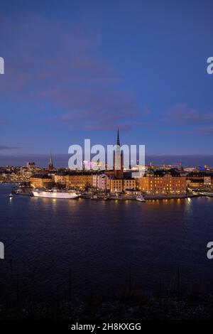 Bellissimo panorama di Stoccolma di notte con mare, edifici, barche e luci notturne della città. Capitale della Svezia fotografata dalla collina. Foto Stock