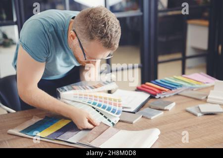 Man designer seleziona il colore delle tende e la tappezzeria dei mobili imbottiti, autore supervisione del progetto di design. Foto Stock