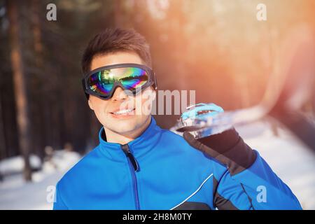 Ritratto di pilota sciatore maschio con sci di fondo sullo sfondo della foresta invernale. Foto Stock