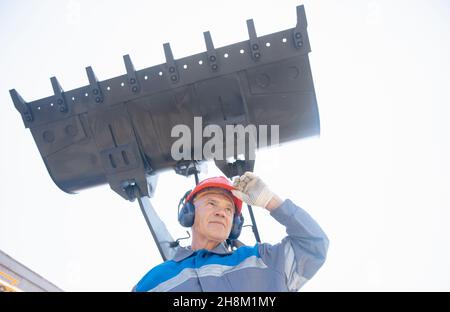 Escavatore in cavalletti per elmetto in attrezzature da costruzione, ritratto uomo industriale concetto. Foto Stock