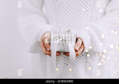 Piccolo regalo nelle palme delle donne, garland festive di sfondo luccicanti luci. Vacanze invernali concetto Capodanno Natale Foto Stock