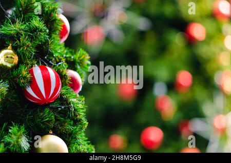 Baubles colorati appesi sull'albero di Natale con sfondo bokeh da un altro albero di Natale più grande. Foto Stock