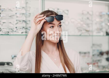 Giovane Donna con occhiali neri punzonati per l'allenamento visivo. Trainer per occhiali perforati. Foto Stock