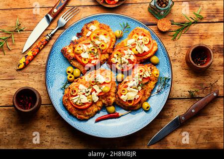 Sottile strato di carne, impanato in pangrattato con formaggio, olive e pomodoro. Delizioso piatto di carne - schnitzel Foto Stock