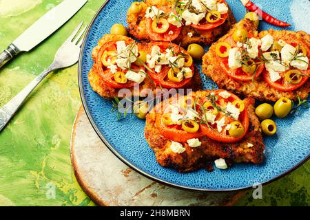 Sottile strato di carne, impanato in pangrattato con formaggio, olive e pomodoro. Piatto di carne - schnitzel Foto Stock