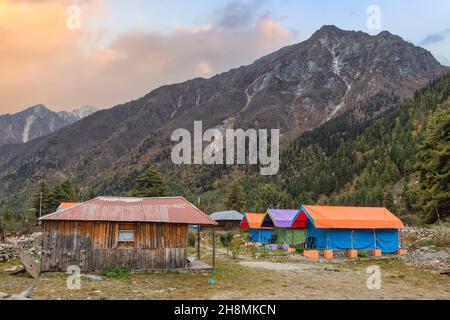 Tende da campeggio per gli amanti dell'avventura e gli escursionisti a Rakchham Himachal Pradesh, India con paesaggio panoramico di montagna Himalaya al tramonto Foto Stock