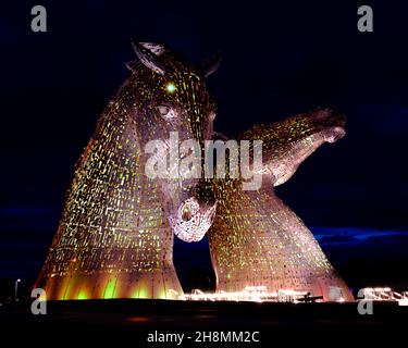 The Kelpies - grandi statue di teste di cavalli che rappresentano gli spiriti d'acqua, illuminati dalle luci circostanti di notte - Falkirk, Scozia, Regno Unito Foto Stock