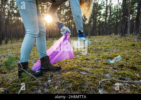 Volontario raccogliere bottiglia di plastica in foresta. L'attivista ambientale sta pulendo la natura dall'inquinamento della plastica. Assuma la responsabilità della natura Foto Stock