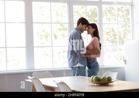 Felice giovane marito e moglie allegro ballare e abbracciarsi insieme in cucina interna Foto Stock