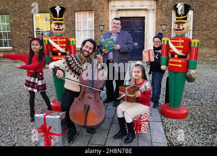 Il violoncellista Patrick Dexter con (da sinistra) Ingrid Nistor (7), Ministro di Stato per gli aiuti allo sviluppo all'estero e Diaspora Colm Brophy, Delia Ioana Tudor (7) e Mickey Riordan (7), al lancio di "essere irlandese a Natale 2021" nel Castello di Dublino. Il programma di 16 giorni, che si svolge dall'8 al 23 dicembre, celebra e sostiene i legami speciali tra gli irlandesi in patria e all'estero nel periodo che va fino a Natale, nonostante l'impatto della pandemia del Covid. Data foto: Mercoledì 1 dicembre 2021. Foto Stock