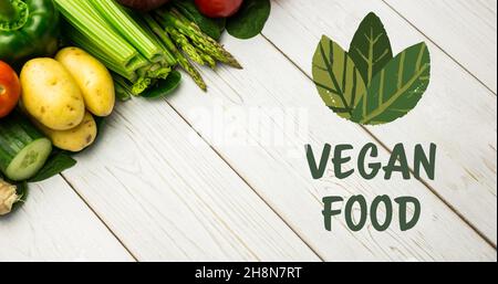 Vista ad angolo alto del cibo vegano simbolo con foglie e verdure fresche su tavola di legno Foto Stock