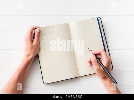 Vista dall'alto della ragazza che crea un piano in un notebook Foto Stock