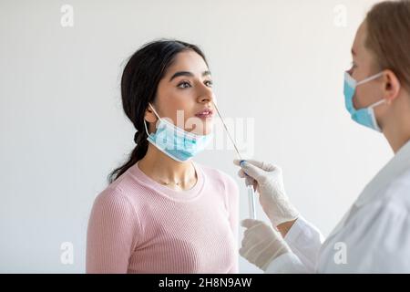 Giovane donna indiana che assume il test COVID-19 con procedura diagnostica con sonda tampone nasale Foto Stock