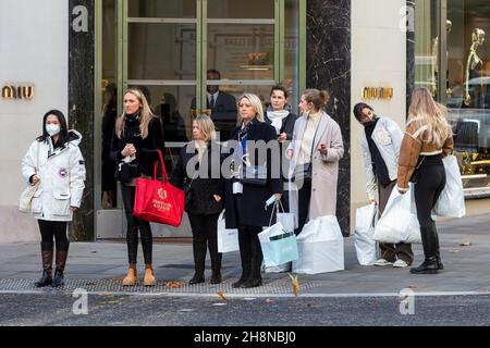 Londra, Regno Unito. 1° dicembre 2021. Acquirenti fuori dal negozio Miu Miu. Decorazioni natalizie in New Bond Street, sede di negozi di lusso. I retailer sperano che l'impatto della variante Omicron non abbia un effetto negativo sul footfall nel periodo di vendita natalizio. Credit: Stephen Chung / Alamy Live News Foto Stock