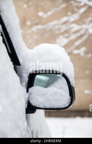 Una piccola auto grigia coperta di neve in una città invernale CIS. Foto Stock