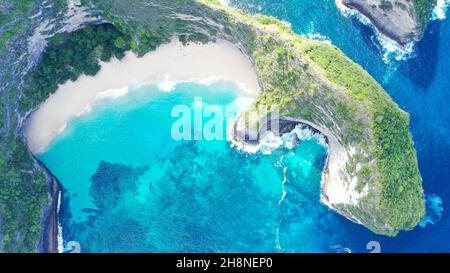 I droni volano sul punto panoramico di Kelingking Beach fino a un promontorio, inclinati su un sentiero sul crinale Foto Stock