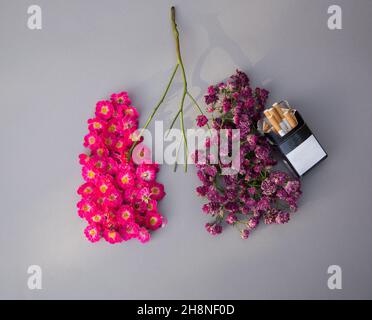 Medicina non fumare concetto. Fiori rosa di rosa su un lato e fiori secchi con pacchetto di sigarette sono disposti a forma di polmoni umani. Vista dall'alto. Foto Stock