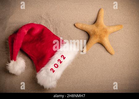 Capodanno 2022 scritto su un cappello Babbo Natale sulla spiaggia sabbiosa. Primo piano Foto Stock