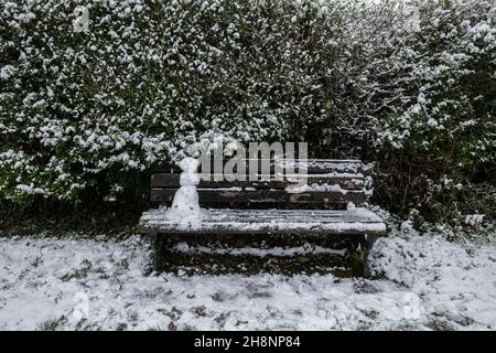 Un mini snowman su una panca parco, Brungerley Park, Clitheroe, Ribble Valley, Lancashire, REGNO UNITO. Foto Stock