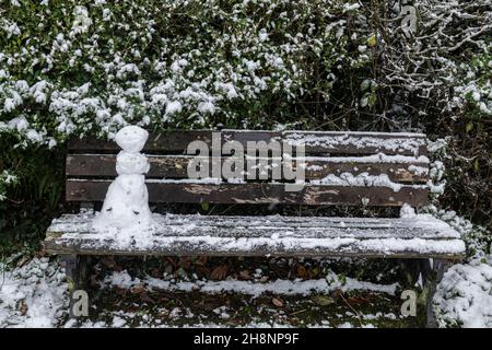 Un mini snowman su una panca parco, Brungerley Park, Clitheroe, Ribble Valley, Lancashire, REGNO UNITO. Foto Stock