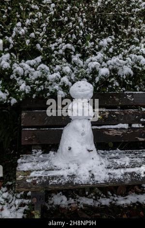 Un mini snowman su una panca parco, Brungerley Park, Clitheroe, Ribble Valley, Lancashire, REGNO UNITO. Foto Stock