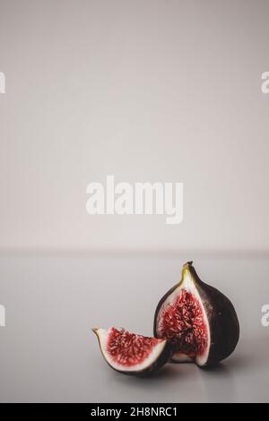 Un minimalismo di fichi. Una fig nelle parti d'angolo tagliate. Fichi freschi sul tavolo Foto Stock