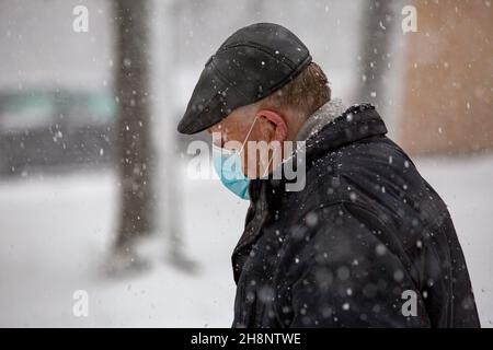 Riga, Lettonia. 1 dicembre 2021. Un uomo che indossa una maschera per il viso cammina nella neve a riga, Lettonia, 1 dicembre 2021. Credit: Edijs Palens/Xinhua/Alamy Live News Foto Stock