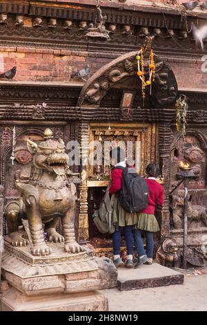 Due giovani ragazze in uniformi scolastiche che adorano al tempio di Bhairab Nath a Bhaktapur, Nepal. Foto Stock