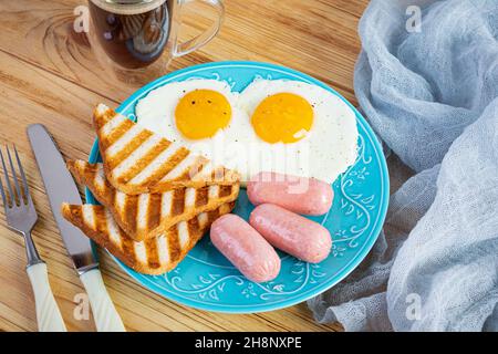 Gustosa colazione con uova, salsicce, toast e una tazza di caffè. Colazione all'americana Foto Stock