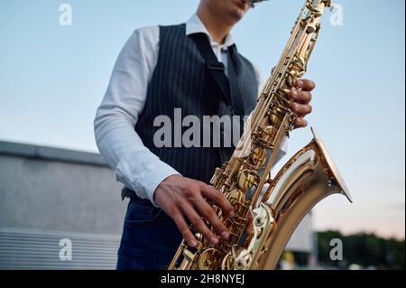 Il sassofonista suona la melodia alle scale della strada Foto Stock