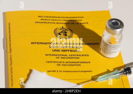 Internationales Impfbuch mit Impfstoffflasche und Spritze auf einem Tisch Foto Stock