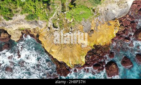 Aereo che scende in una gola tropicale con vista completa di una cascata frettolosa circondata da pareti frastagliate di roccia ricoperte di folta vegetazione con fresco Foto Stock