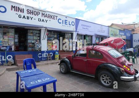 Red Volkswagen coleottero auto al Mini negozio di mercato a Cusco Perù con coca cola rosso cofanatura tettuccio rosso sedia auto sedile seduta blu segni di plastica Foto Stock