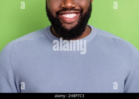 Foto di allegro ragazzo africano vestito maglione grigio sorridente mostrando denti bianchi isolato sfondo di colore verde Foto Stock