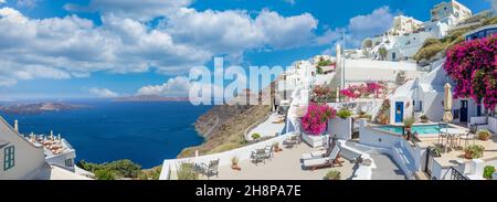 Paesaggio panoramico incredibile, vacanza di lusso. Città di Oia sull'isola di Santorini, in Grecia. Tradizionale e famosa architettura bianca e fiori rosa Foto Stock