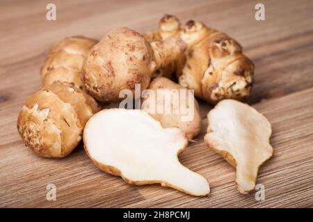 Carciofi di Gerusalemme tagliati interamente su tavola di legno carciofi di Gerusalemme, Topinambur, bruni, tuberi, vegetali, patate, aperte, tagliate all'interno Foto Stock