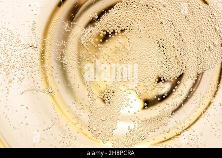 Macro di champagne in un bicchiere di vetro, spumante, champagne, bollicine, dettaglio, ascend, multiplo, bianco, sfondo Foto Stock