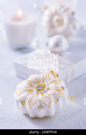 Sistemazione di ornamenti natalizi, candele e smal presente in bianco nevoso Foto Stock