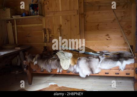 Gudvangen, Norvegia - circa Settembre 2021: Interno di una casa vichinga con coperta di pelliccia e arco sul letto Foto Stock