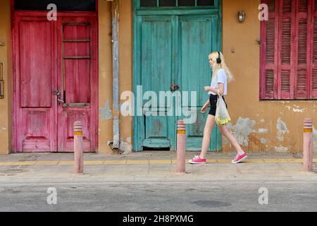 Giovane adolescente che cammina lungo la strada della città vecchia, vintage porte sfondo Foto Stock